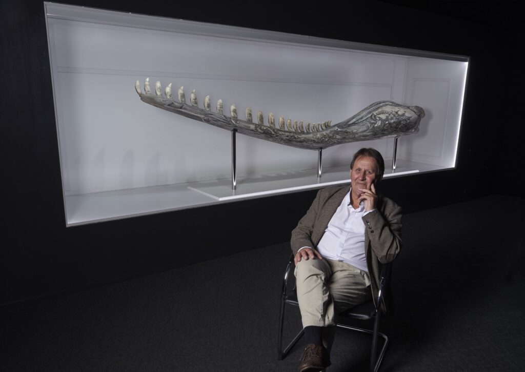 Gary Tonkin sitting in front of his 4 metre scrimshaw sperm whale jawbone