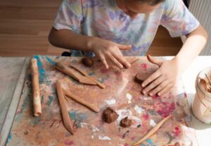 Child playing with clay and tools on a table